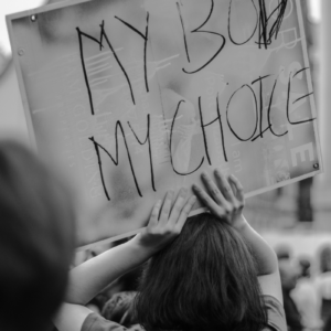 black and white photo of a woman holding a protest sign declaring my body my choice at a protest